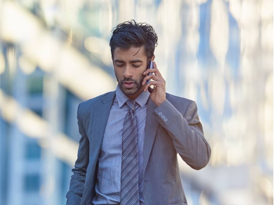 Man in a suit and tie talking on a mobile device.